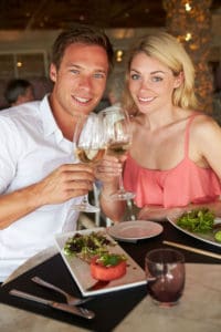 A man and woman holding wine glasses at a restaurant.